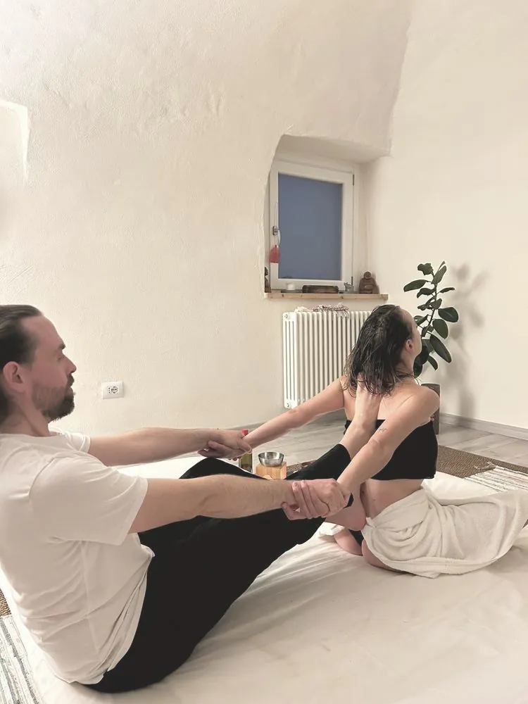 Luca e una cliente durante un allungamento di Yoga Ayurvedico su futon